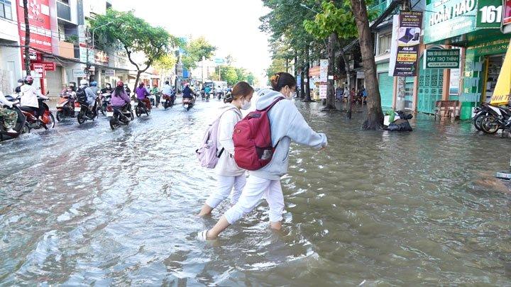 Các em học sinh chật vật lội qua những đoạn nước dâng cao.