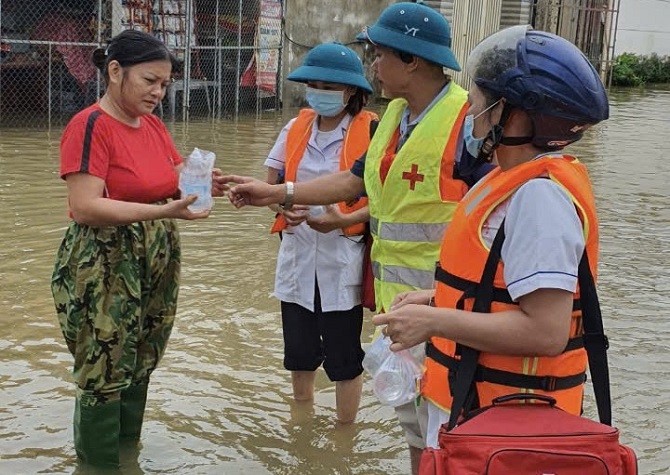 Cán bộ y tế Trạm y tế thị trấn Xuân Mai cấp phát thuốc cho người dân vùng ngập lụt.