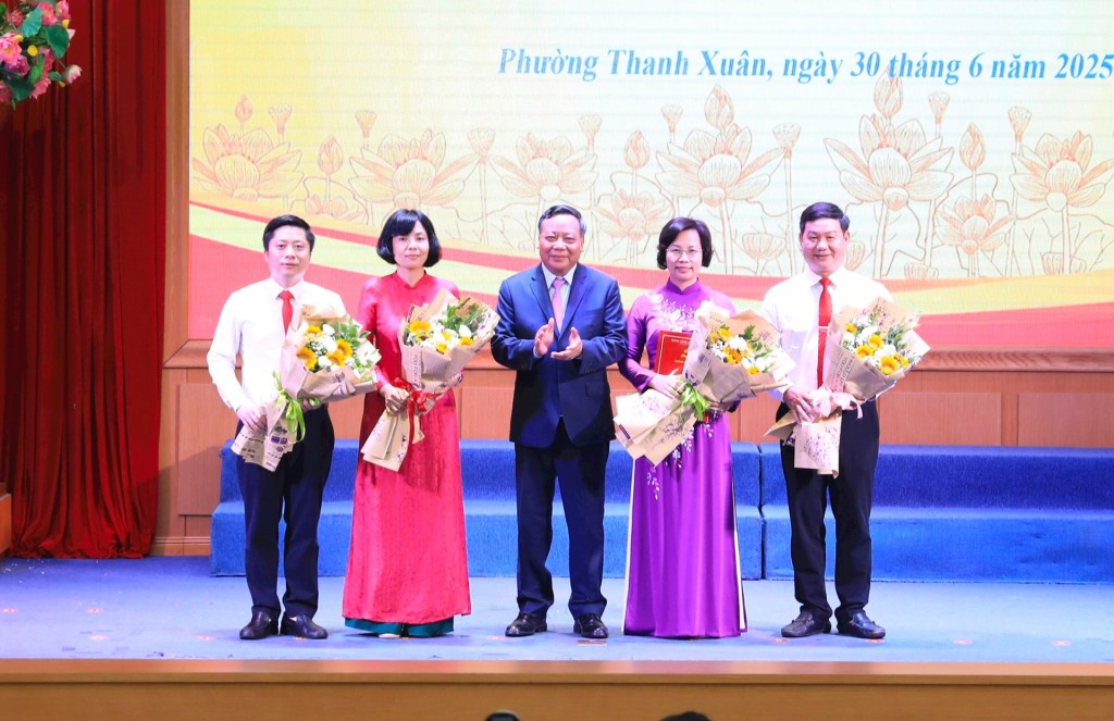 Phó Bí thư Thường trực Thành ủy Hà Nội Nguyễn Văn Phong trao Quyết định và tặng hoa chúc mừng lãnh đạo phường Thanh Xuân. Ảnh: Quang Thái