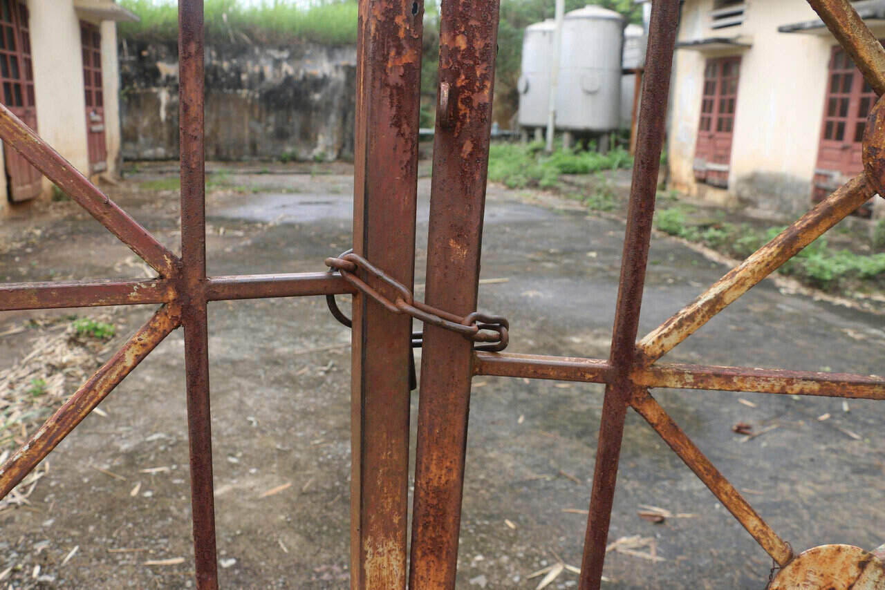 Cánh cổng sắt hoen gỉ, đóng cửa nằm im lìm. Ảnh: Yên San