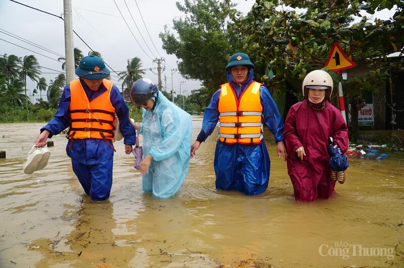 Lực lượng chức năng hỗ trợ đưa người dân qua khu vực ngập úng.
