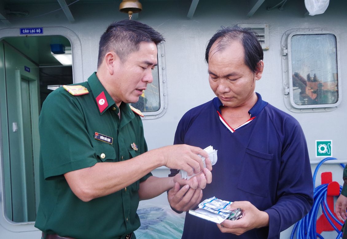 Quân y trên tàu BV98308TS cấp thuốc và hướng dẫn sử dụng cho ngư dân Võ Hoàng Rớt. Ảnh: Văn Đường